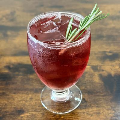 Iced red beverage with rosemary.
