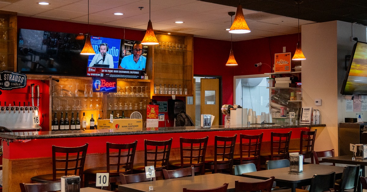 Interior, sushi bar, stools in line, screen tv above, drink rack behind