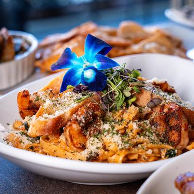 Shrimp and crab pasta with Parmesan, garlic bread, and orchid garnish.