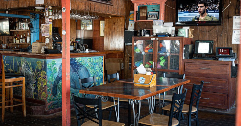 Interior, tables, chairs, counter, lighting, wall TV, registers, stacked glasses and bottles