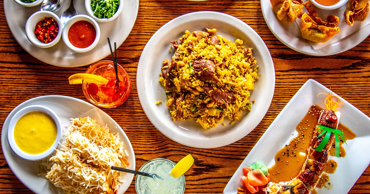 Pineapple fried rice served on the table alongside a cocktail and other dishes