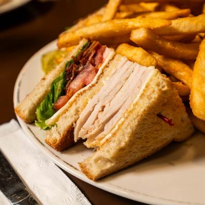 Club sandwich served with fries on a white plate, close-up.