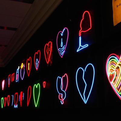 Colorful neon heart designs on a black wall.