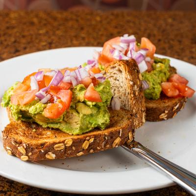 Avocado toast topped with tomatoes and onions.