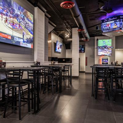 The interior of Tie Breakers, featuring bar tables and chairs, and multiple TVs showing sports.