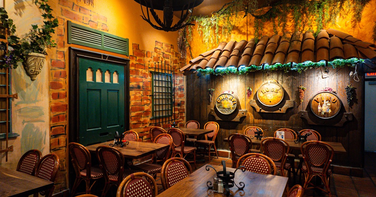 Cozy restaurant interior with rustic decor, wooden tables, wicker chairs, brick walls, wine barrels