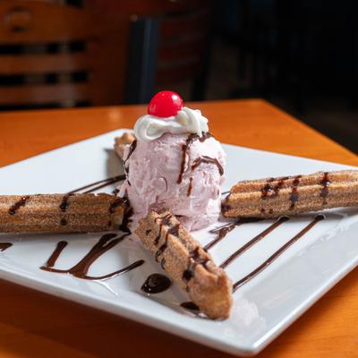 Churros served with ice cream, whipped cream and chocolate drizzle.