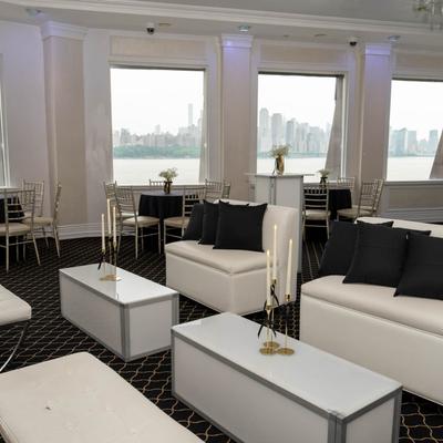 Waterfront lounge with white sofas and black pillows.