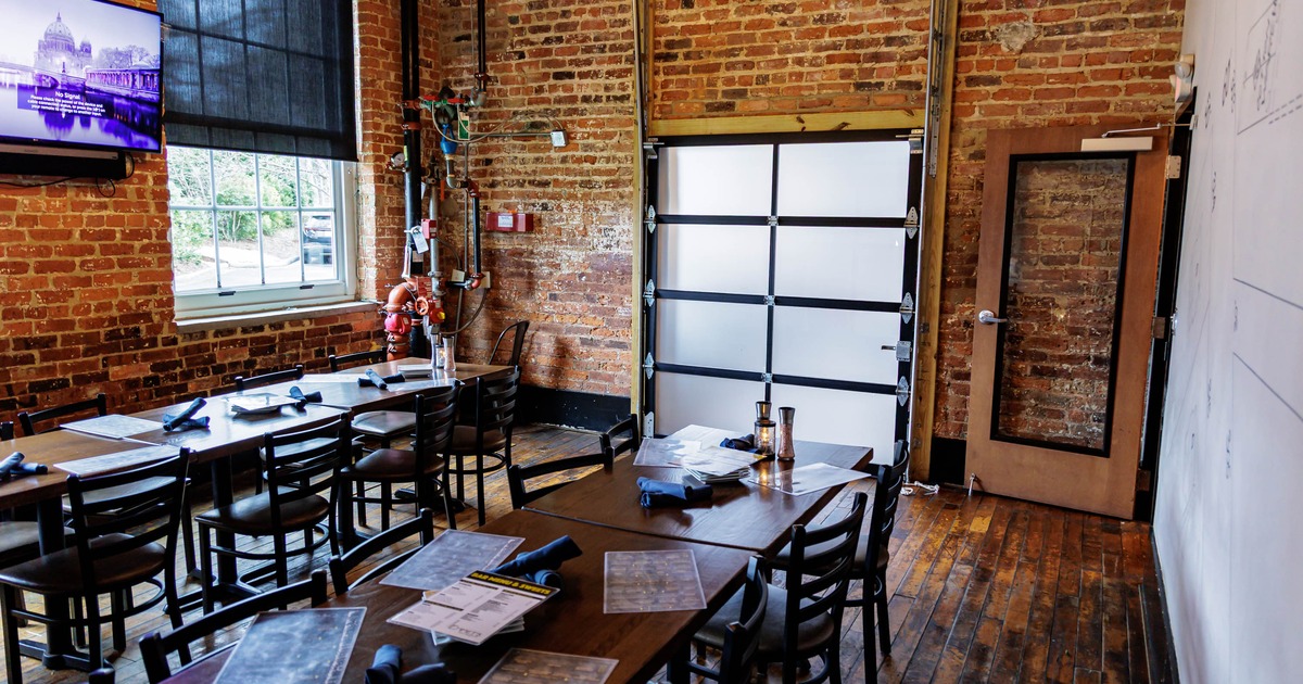 Dining area with brick walls, wooden tables and an industrial garage door.