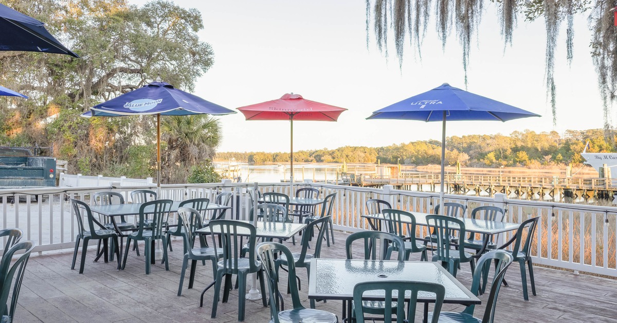 Outdoor seating area with tables and umbrellas on a deck by the water