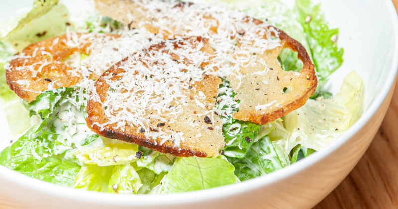 Salad with toast and lettuce, topped with grated cheese, bowl closeup