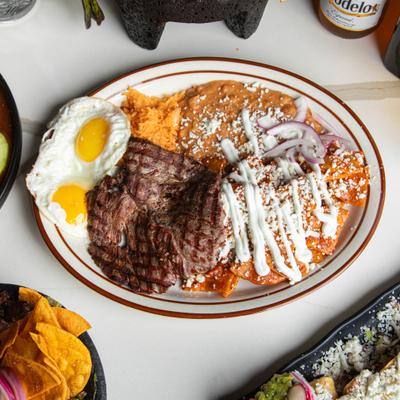 Chilaquilles served with carne asada, fried eggs, rice and beans.
