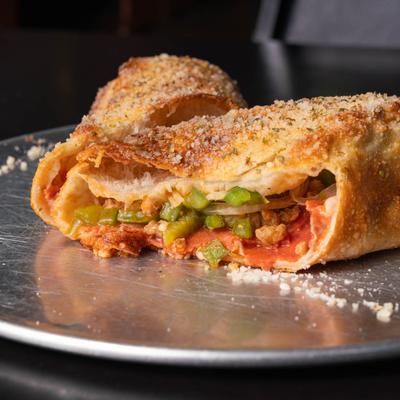 Baked calzone with sausage, peppers, onions, and melted cheese.