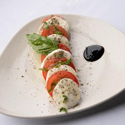 Caprese salad with fresh mozzarella, fresh basil, tomato and oregano.
