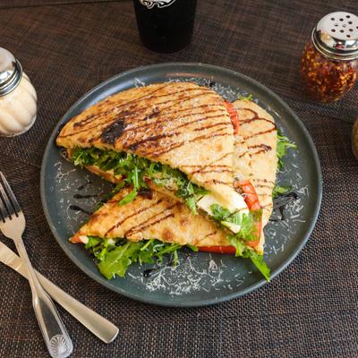 Panini with arugula, mozzarella, tomatoes, basil, olive oil, and pesto.