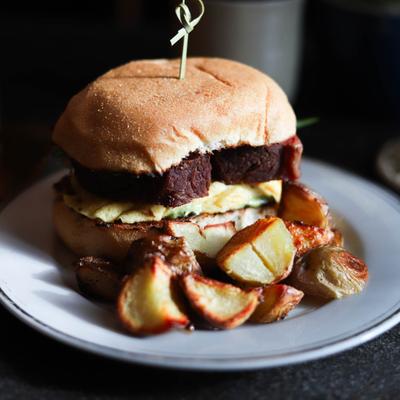 Corned beef sandwich on a sweet Filipino bread roll, served with roasted potatoes.