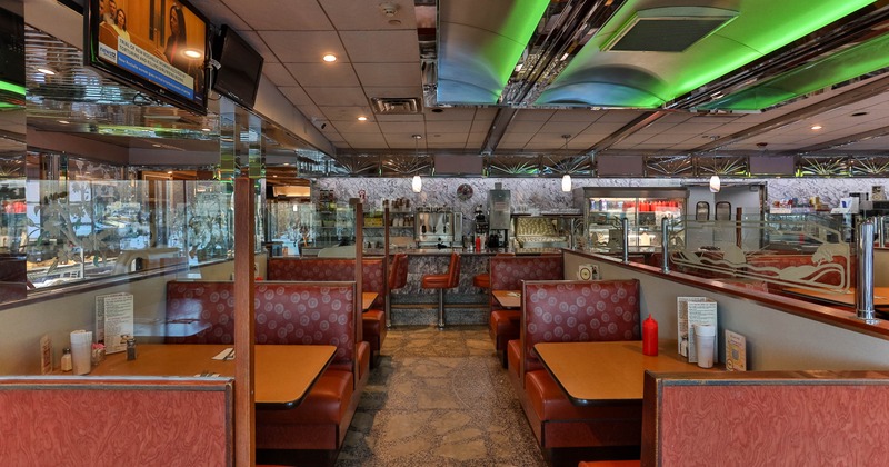 Interior of a classic styled diner with red booths, chrome accents, and a view of the counter area