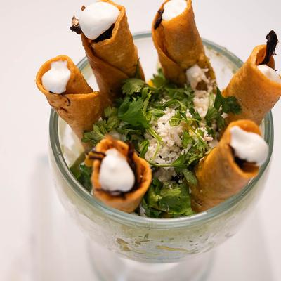 Fried rolled tortillas stuffed with meat, served with lettuce, guacamole, cilantro, cheese.