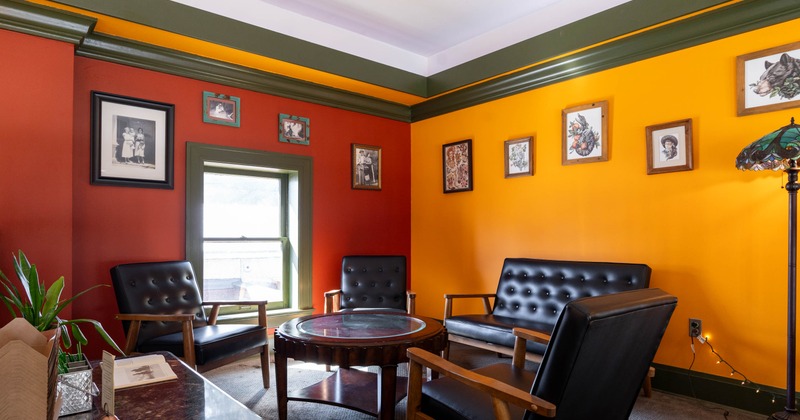 A lounge with red and yellow walls, and black leather seating