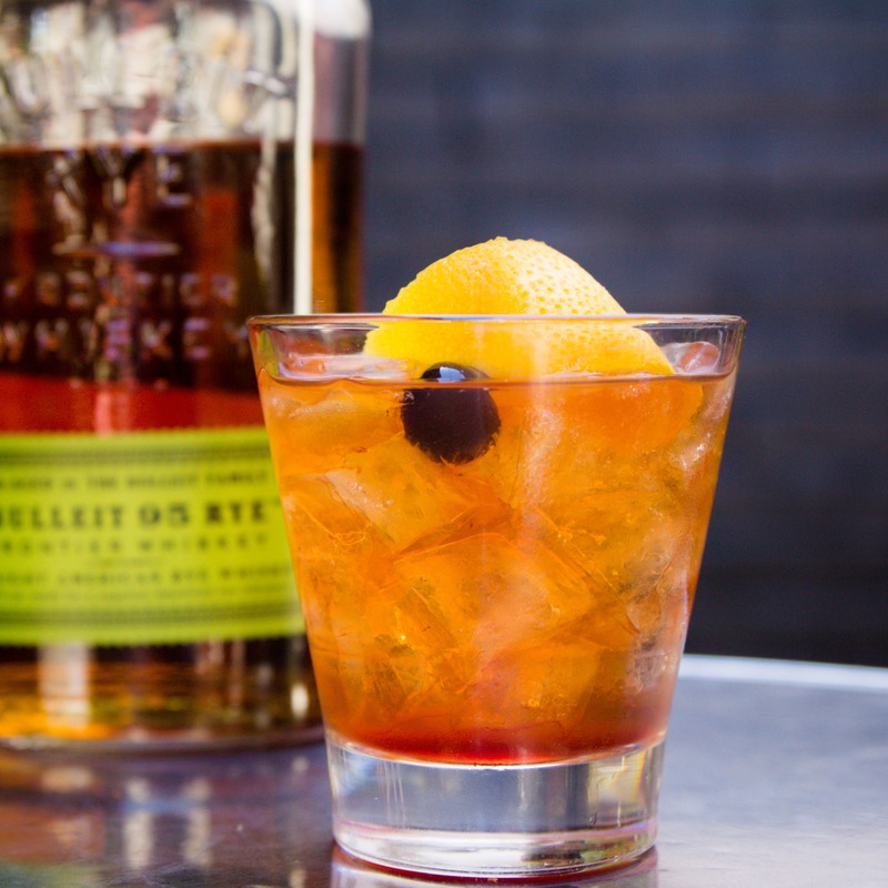 Orange cocktail with ice, olive and lemon peel