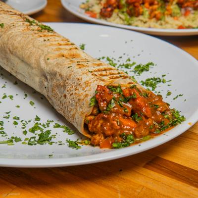 Butter Chicken Wrap garnished with fresh herbs, close-up.