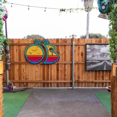 We Be OB trademark and decorative objects on a wooden fence.