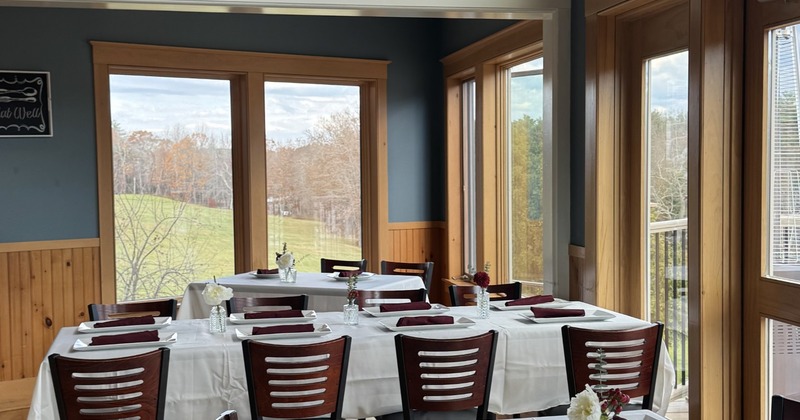 Interior with Christmas decorations; wooden tables and chairs and large windows with outdoor views