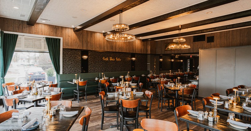 Interior, dining area, wooden top tables for four, banquette bench with tables, chandeliers