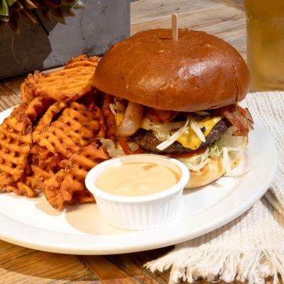 Cheeseburger served with crispy waffle fries and chipotle mayo on a white plate.
