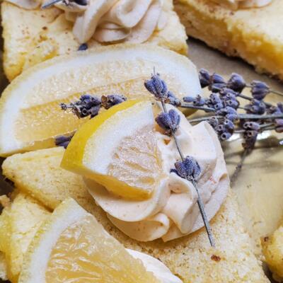 Close-up of a lemon dessert topped with whipped cream and a sprig of lavender.
