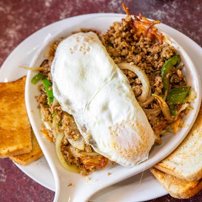 Italian sausage peppers and onions skillet, topped with fried eggs, served with toast.