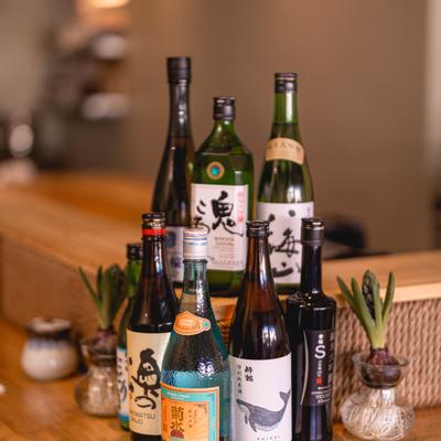 Assorted sake bottles on a decorated wooden counter.