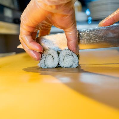 Chef cutting sushi roll.
