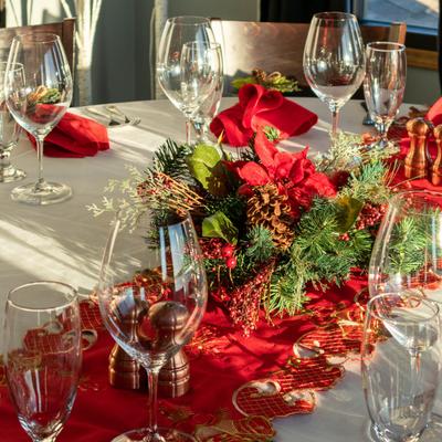 Festive table setting with empty wine glasses, red napkins, and a central Christmas centerpiece.