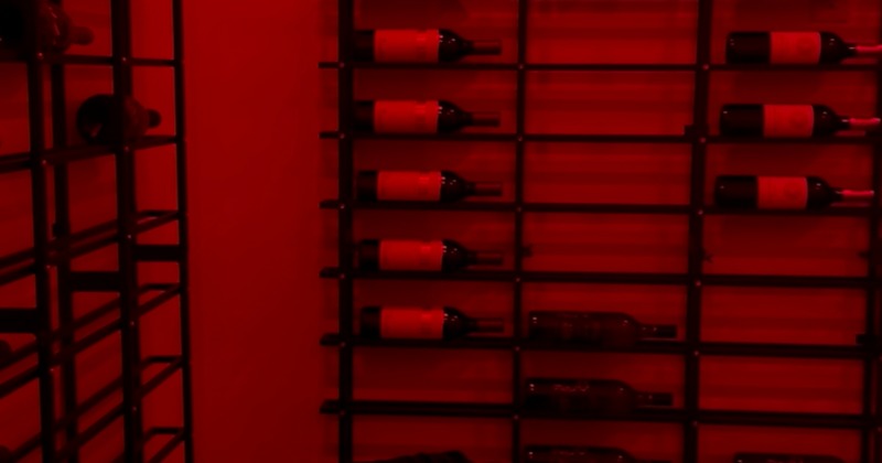 A modern wine cellar, featuring bottles stored on metal racks under red lighting