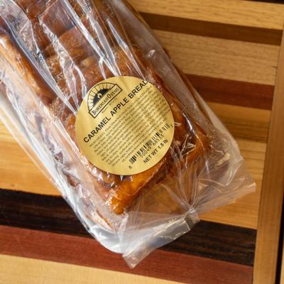 Packaged caramel apple bread sitting on a multi-tone wooden table.