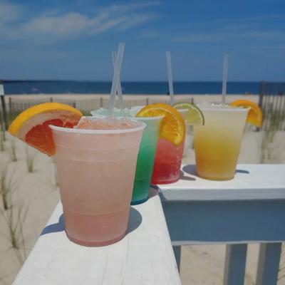 Various cocktails served in plastic glasses in outdoor setting.