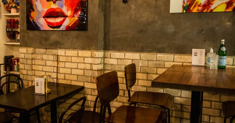 Interior, tables and seats by a wall with paintings