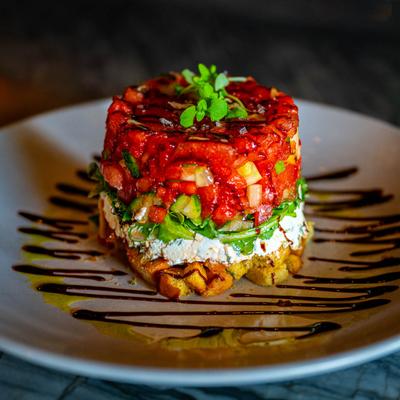 Layered salad stack with vegetables and drizzle.