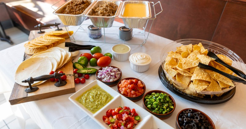 Catering table with tortillas and various taco toppings on it