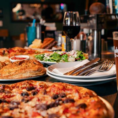 Pizza, calzone, salad, and red wine on a restaurant table.