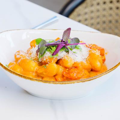 Gnocchi served in a creamy tomato sauce, garnished with cheese and microgreens.