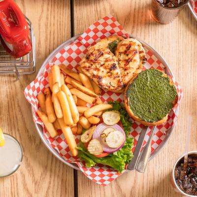 Grilled chicken sandwich with lettuce, tomato, pickles, pesto, and fries.