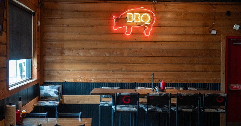 Interior, dining area, high seating table with stools, wood coated walls, ''BBQ'' neon sign