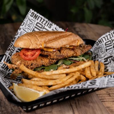 Soft shell crab sandwich served with lemon wedge and fries.