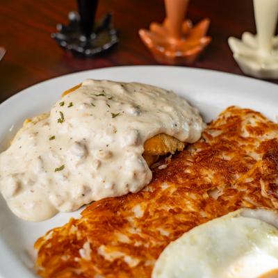 Chicken fried steak served with hash browns and a fried egg.