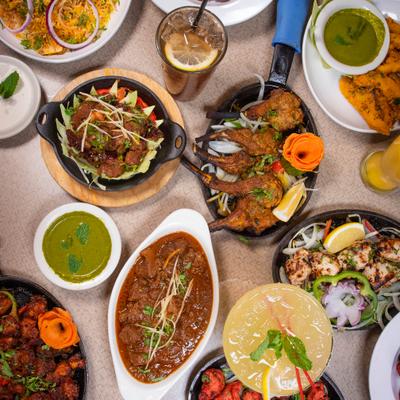 An array of diverse Indian dishes, curries, and drinks on a table, overhead view.