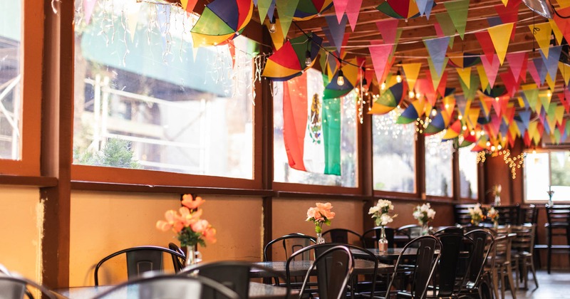 Interior, tables and chairs,  window seating, colorful flag pennants hanging from the ceiling