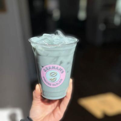 A hand holding an iced blue drink in a plastic cup labeled with Graham's Coffee Parlor.