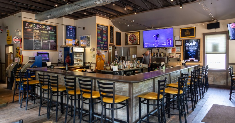 Interiror, bar, bar stools all around, screen tv above